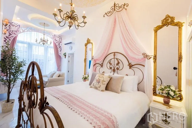 联排别墅 出租在Lat Phrao, Bangkok - 卧室设锻铁床与粉色帷幔，水晶吊灯及金框落地镜。