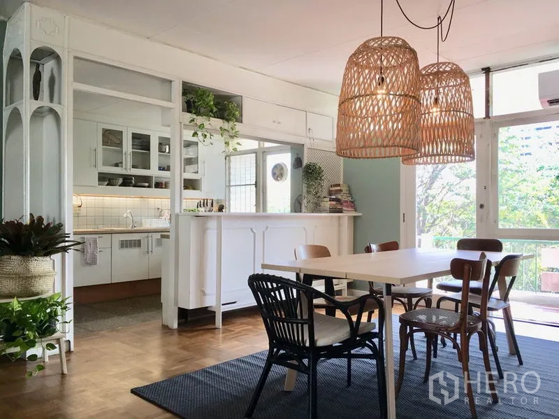 Apartment for rent in Khlong Toei, Bangkok - Dining space beside a semi-open kitchen and breakfast bar, with woven pendant lights and garden views.