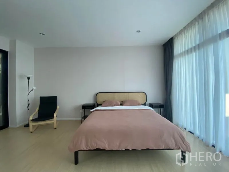 Townhouse for rent in Saphan Sung, Bangkok - Bedroom with bed, side tables, floor lamp and expansive windows for natural light.