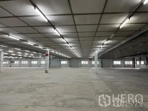 Factory for rent in Phra Pradaeng, Samut Prakan - Expansive warehouse interior with concrete flooring, bright strip lighting, and support columns.