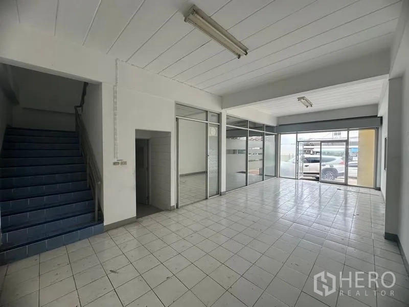Factory for rent in Khlong Luang, Pathum Thani - Ground-floor office lobby with blue stairway, glass frontage and tiled floor.
