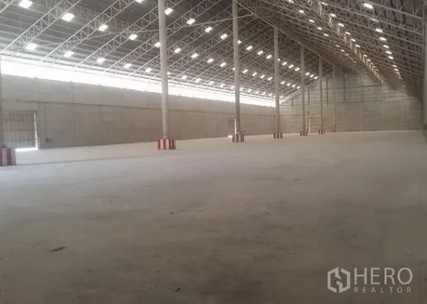 货栈 出租在Phra Nakhon Si Ayutthaya - 仓库内部，钢桁架高屋顶与天窗采光，开阔混凝土地面。
