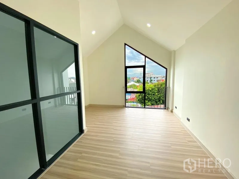 带办公室的家 出租或出售在Bang Na, Bangkok - 带不对称大窗与迷你阳台的房间，旁为玻璃隔断楼梯间。