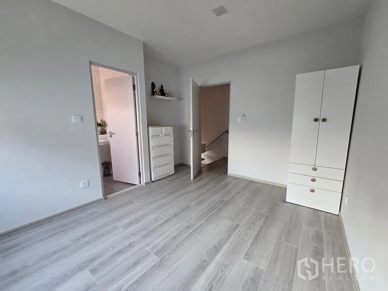 独立式住宅 出租在Bang Phli, Samut Prakan - 楼上空房，衣柜、带卫浴的门与灰色木地板。