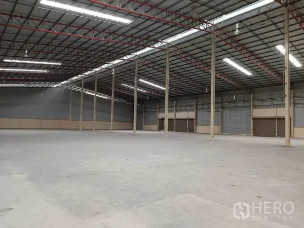 工厂 出租在Samut Prakan - 工厂内部钢结构与通风墙体布局，地面平整，多个大型卷帘门便于装卸。