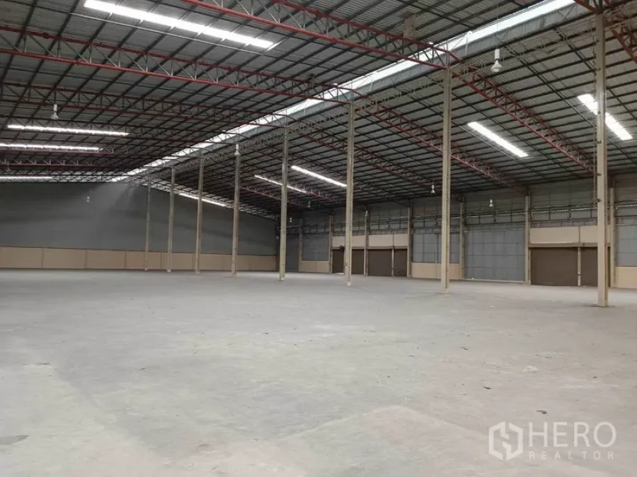 工厂 出租在Samut Prakan - 工厂内部钢结构与通风墙体布局，地面平整，多个大型卷帘门便于装卸。