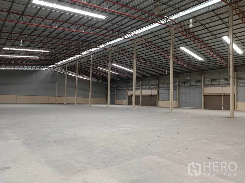 工厂 出租在Samut Prakan - 工厂内部钢结构与通风墙体布局，地面平整，多个大型卷帘门便于装卸。