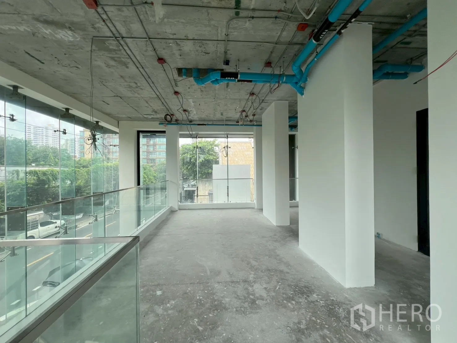 พื้นที่ขายปลีก ให้เช่า - ทางเดินชั้นลอยยาว มีเสาและกระจกพาโนรามาคู่ถนน