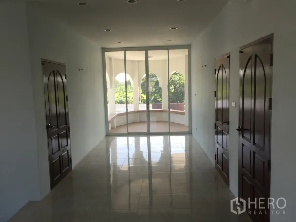 独立式住宅 出租在Saphan Sung, Bangkok - 二层走廊，拱形木门与玻璃推门连接弧形阳台，眺望绿景。