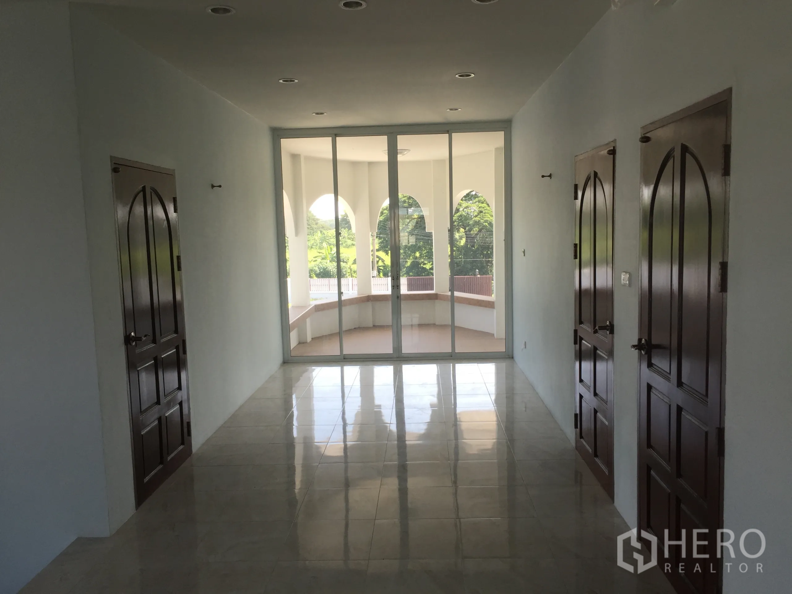 独立式住宅 出租在Saphan Sung, Bangkok - 二层走廊，拱形木门与玻璃推门连接弧形阳台，眺望绿景。