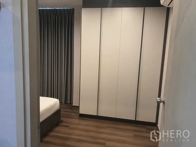 Condominium for rent - Bedroom featuring a large built-in white wardrobe and dark wood floors.