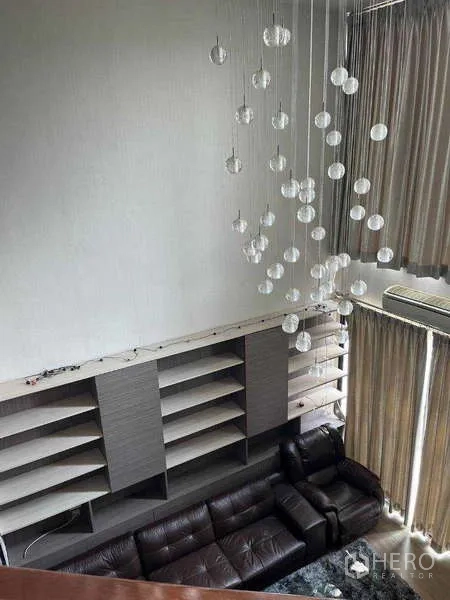 ทาวน์เฮาส์ ให้เช่าในKhlong Toei, Bangkok - ห้องนั่งเล่นเพดานสูง โซฟาหนัง ชั้นวางของ และโคมไฟระย้าทรงลูกแก้ว ถ่ายจากชั้นบน