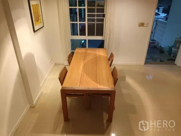 Townhouse for rent in Bang Kapi, Bangkok - Dining room with a solid wood table for four placed beside a large window.