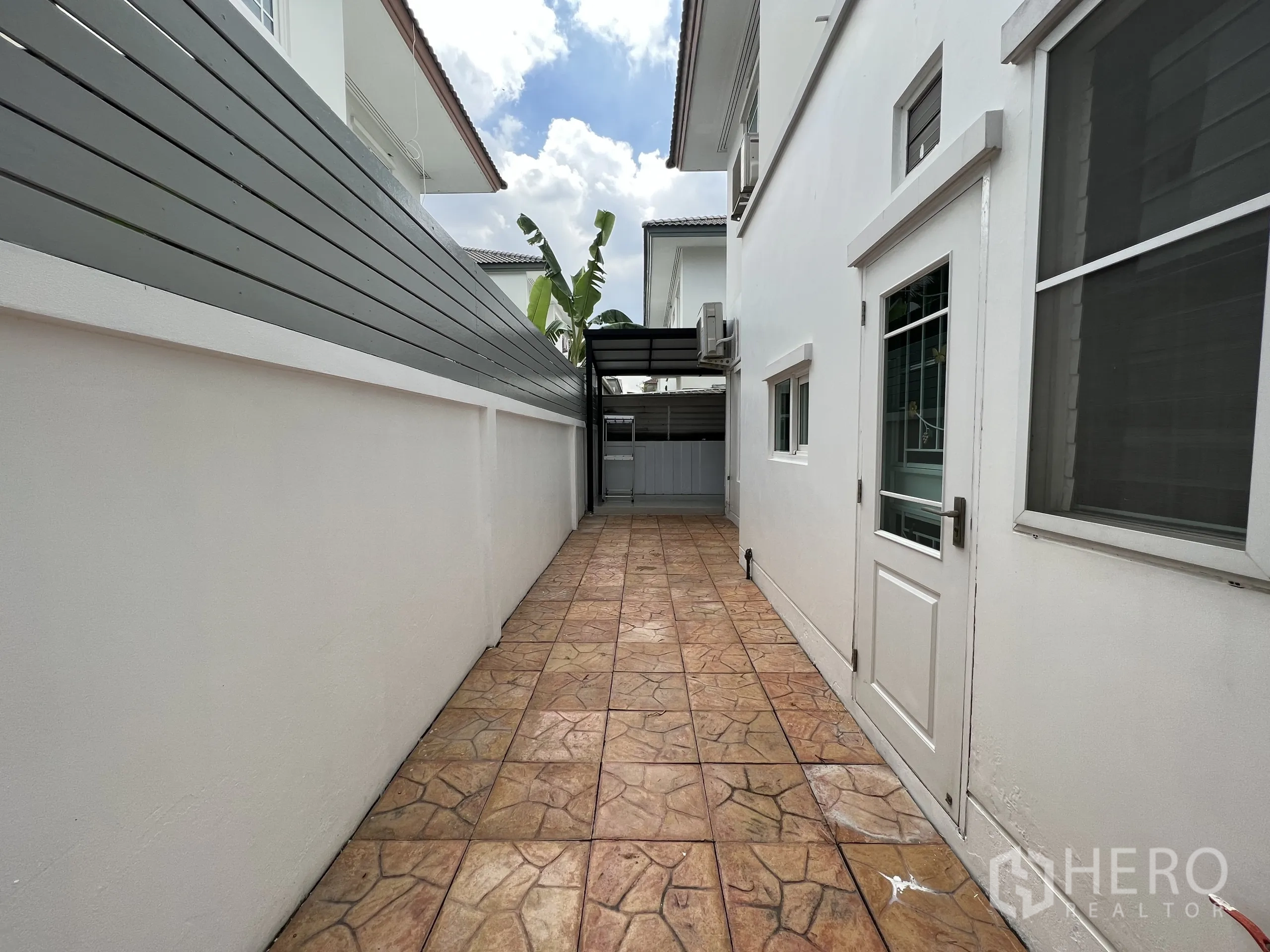 Detached House for rent in Bang Kapi, Bangkok - Side walkway with patterned tiles and a white side door along the house.