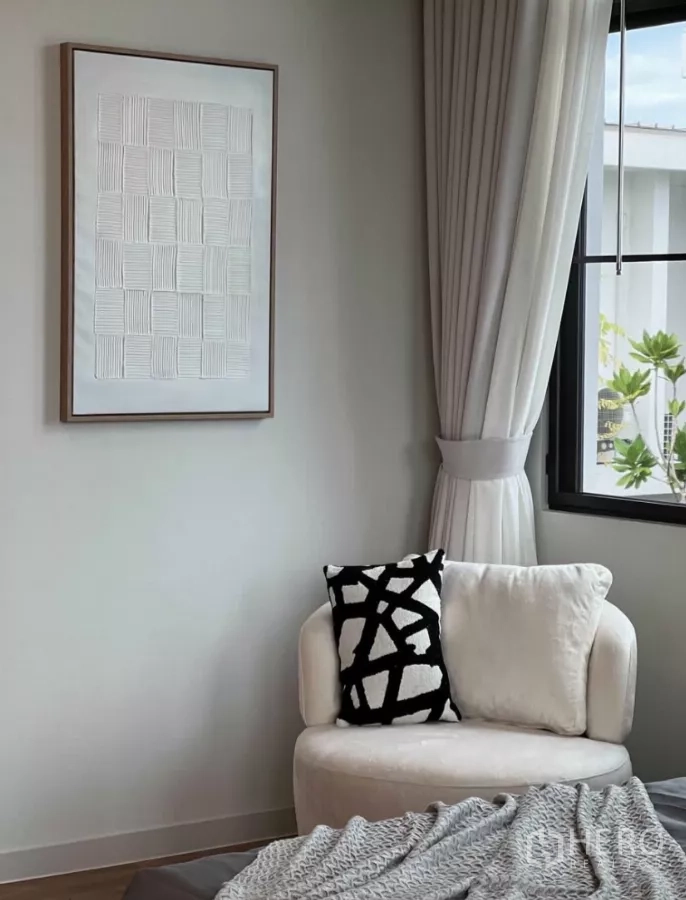 Detached House for rent in Samut Prakan - Bright reading corner with a white accent chair by the window and full-length curtains.