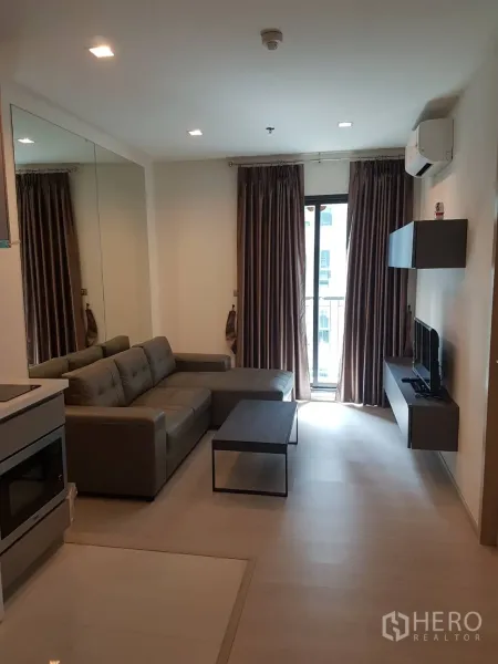 คอนโด ให้เช่าในKhlong Toei, Bangkok - ห้องนั่งเล่นสว่าง โซฟาเข้ามุม โต๊ะกลาง ชั้นวางทีวี และประตูกระจกสู่ระเบียง