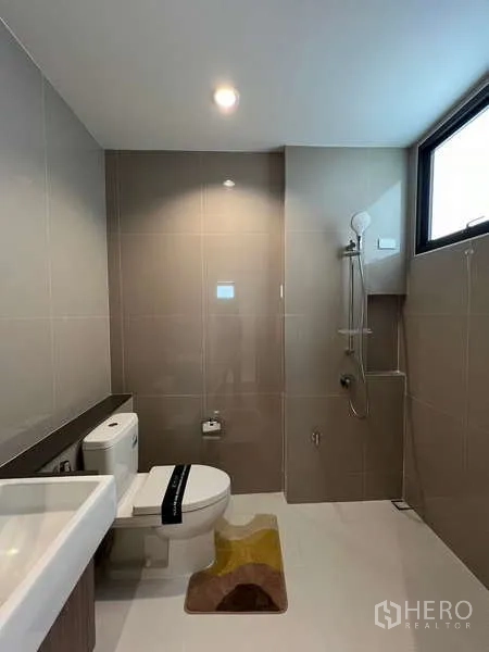 Detached House for sale in Saphan Sung, Bangkok - Clean tiled bathroom with a window and walk-in shower.