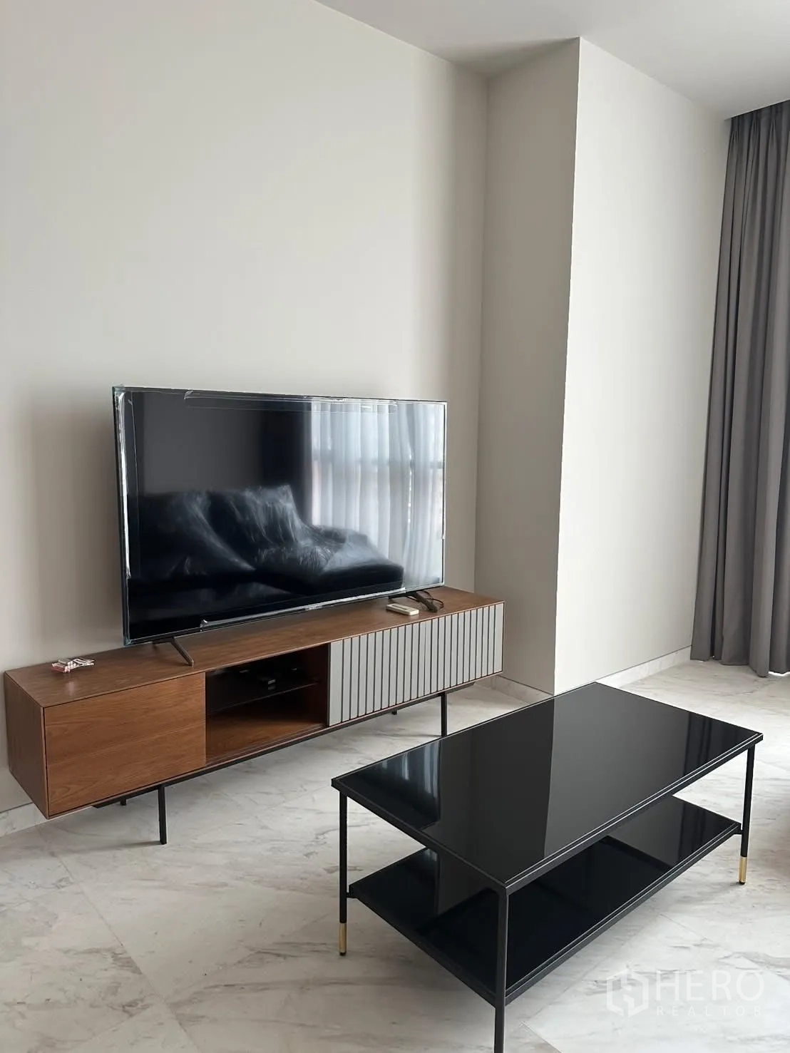Condominium for rent or sale in Watthana, Bangkok - Living area TV console and glossy black coffee table on marble floor.