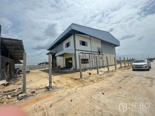 คลังสินค้า ให้เช่าในMueang Samut Prakan, Samut Prakan - ภาพมุมกว้างของโกดังสองชั้นหลังคาเมทัลชีท พร้อมเสาแนวรั้วติดถนนคอนกรีต
