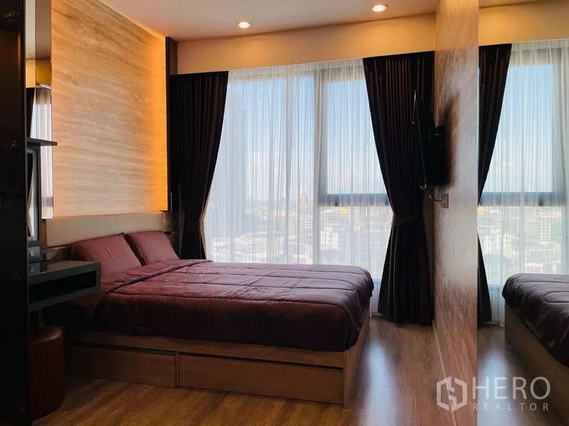 公寓 出租在Bang Na, Bangkok - 主卧配大床与暖色灯光，落地窗眺望城市景色。