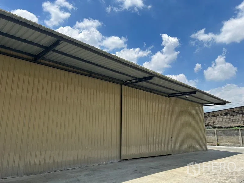 คลังสินค้า ให้เช่าในPhra Khanong, Bangkok - ภาพระยะใกล้ผนังเมทัลชีทและหลังคากันสาดของโกดัง ข้างลานขนถ่ายสินค้า.