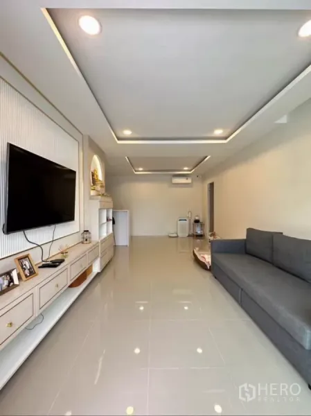 บ้าน ให้เช่าหรือขายในKhlong Toei, Bangkok - ห้องนั่งเล่นสว่าง ฝ้าเพดานหลุมฝังไฟ พื้นกระเบื้องเงา ผนังบิลท์อินวางทีวีและโซฟาสีเทา.