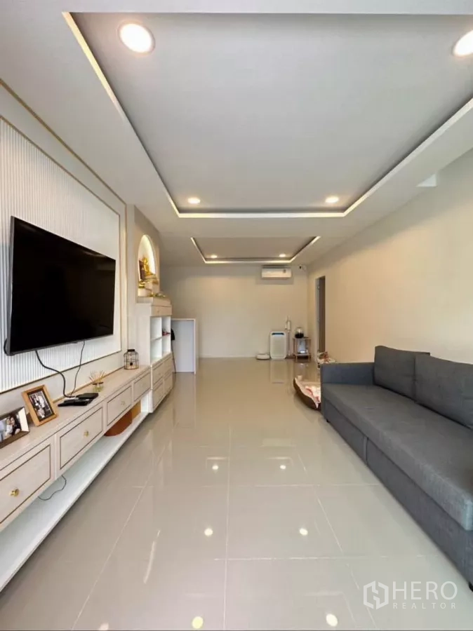 บ้าน ให้เช่าหรือขายในKhlong Toei, Bangkok - ห้องนั่งเล่นสว่าง ฝ้าเพดานหลุมฝังไฟ พื้นกระเบื้องเงา ผนังบิลท์อินวางทีวีและโซฟาสีเทา.