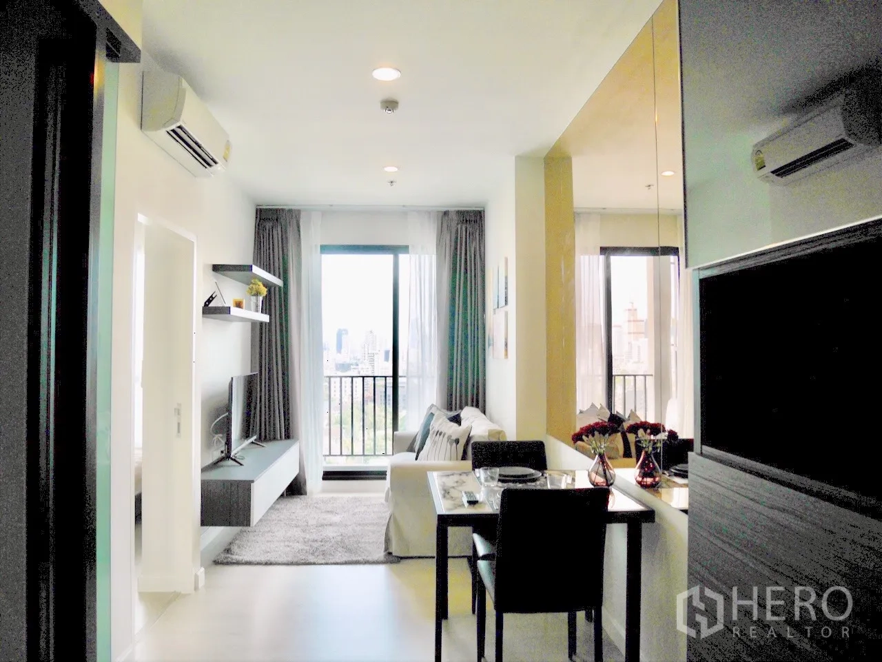 Condominium for rent in Pathum Wan, Bangkok - Open-plan lounge and dining leading to a balcony with Bangkok skyline view.