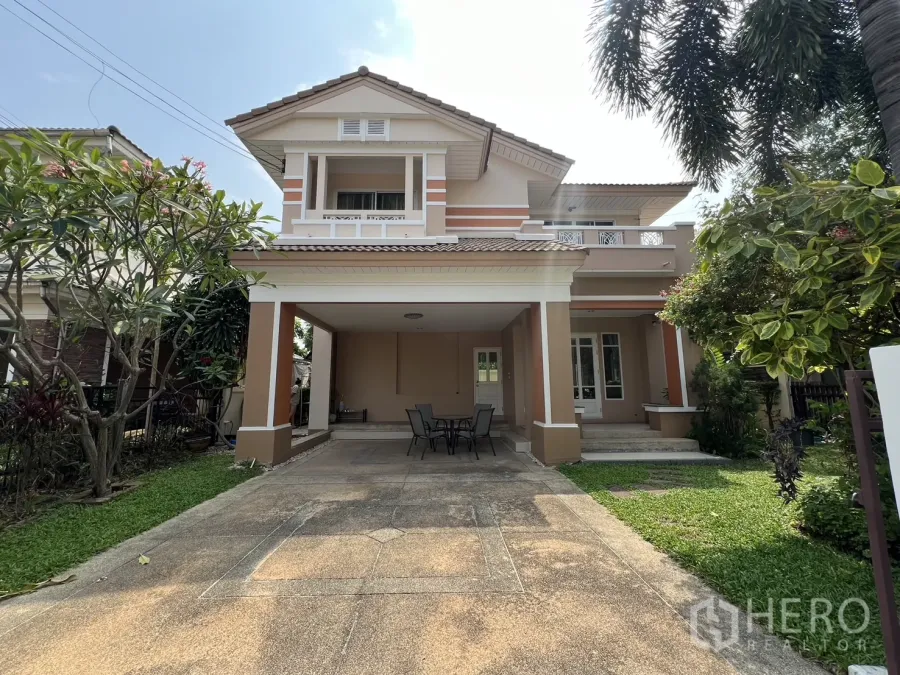 บ้าน ให้เช่าในLat Krabang, Bangkok - ด้านหน้าบ้านเดี่ยวสองชั้น พร้อมที่จอดรถมีหลังคา ทางรถเข้ากว้างและสนามหญ้า