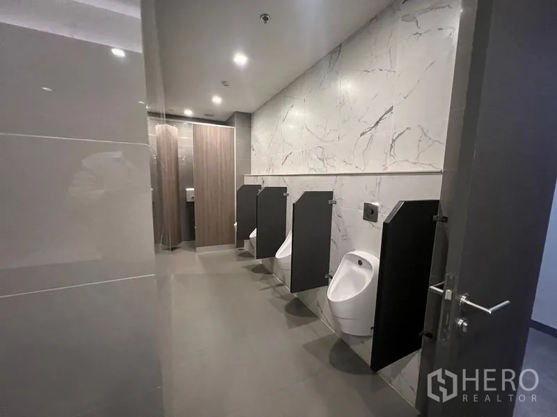 Office Space for rent - Men’s restroom with urinals and partition screens.