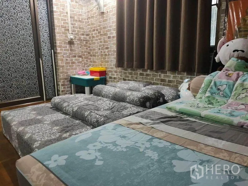 Townhouse for sale in Bang Phlat, Bangkok - Cozy bedroom with brick-pattern walls, sliding wardrobe and floor mattress.