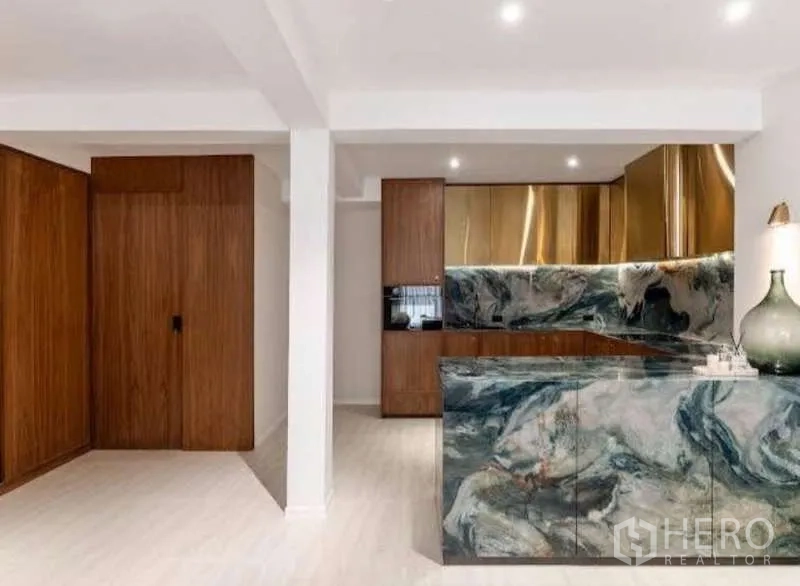 Townhouse for sale in Sathon, Bangkok - Designer kitchen with marble waterfall island, brass cabinetry and wood finishes.