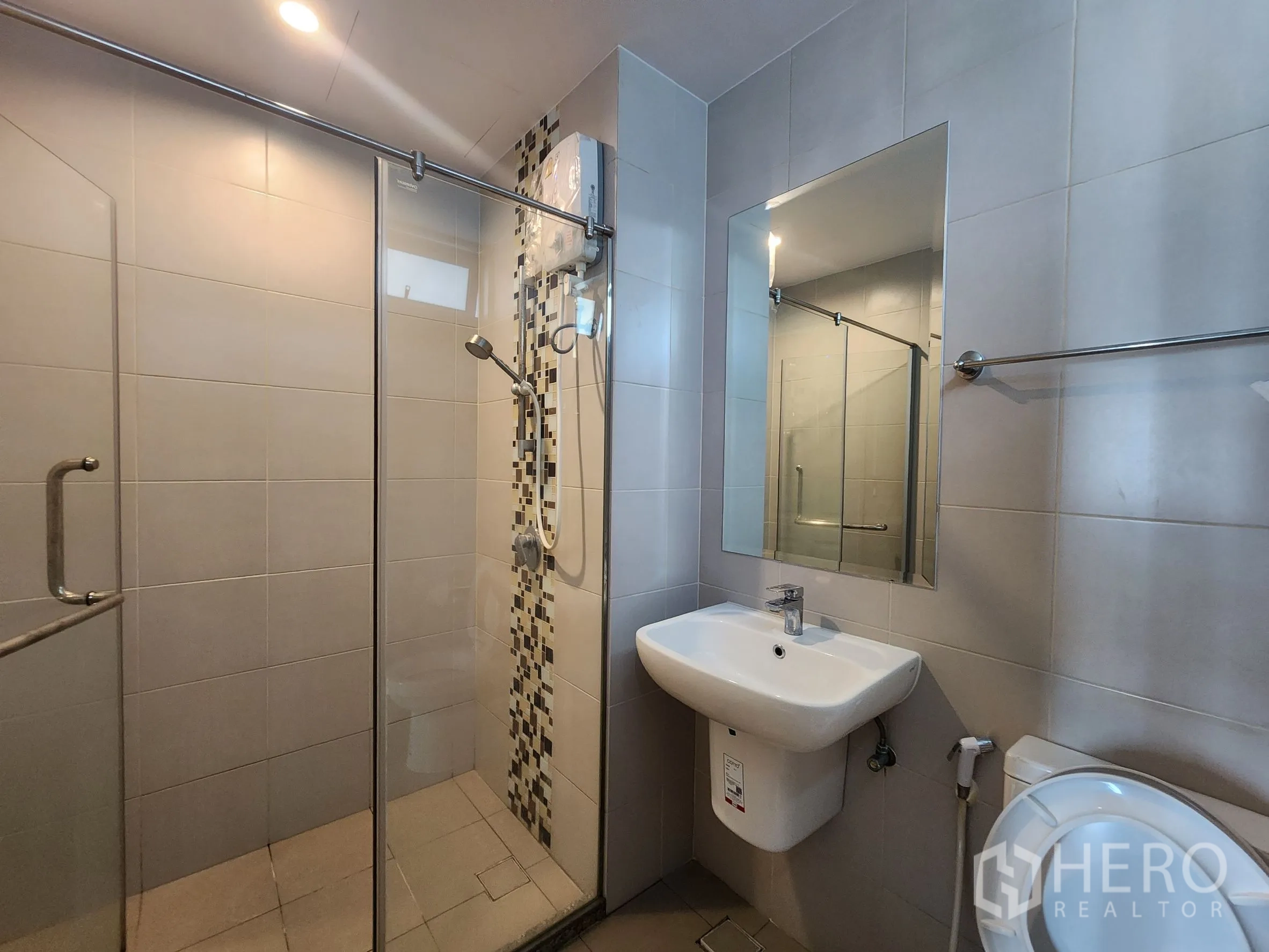 คอนโด for rent in Huai Khwang, Bangkok - ห้องน้ำกั้นอาบน้ำกระจก ไทล์ลายตกแต่งแนวตั้ง อ่างล้างหน้า และโถสุขภัณฑ์