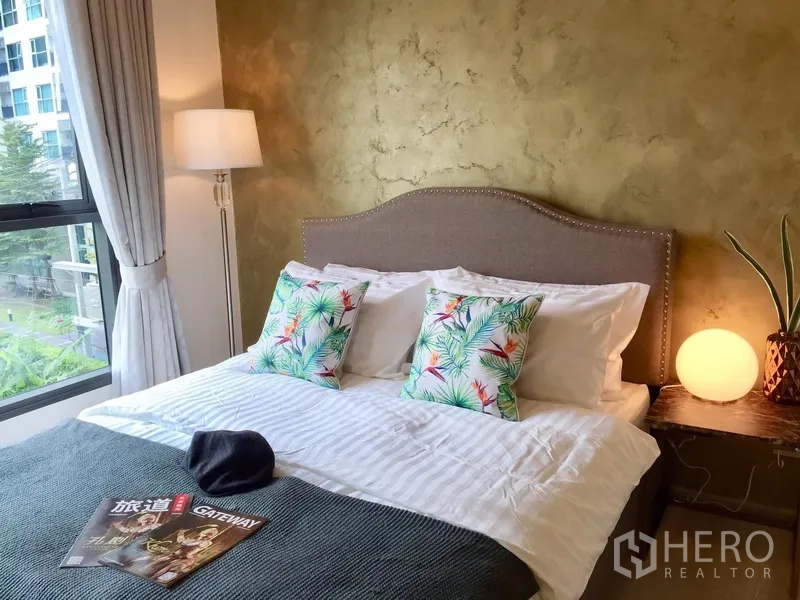 คอนโด ให้เช่าในKhlong Toei, Bangkok - ห้องนอนสว่าง ผนังลายปูนเปลือยสีทอง เตียงคู่ หมอนลายพิมพ์ และโคมไฟหัวเตียง