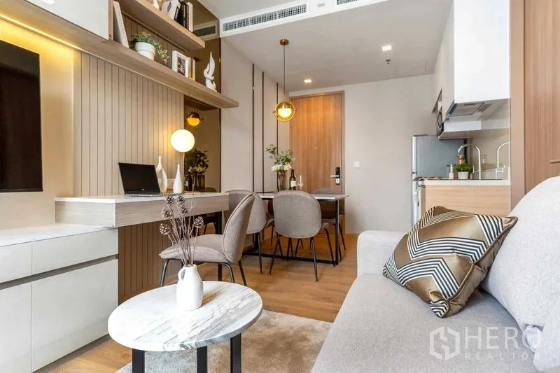 Condominium for rent in Watthana, Bangkok - View from sofa toward dining and kitchen with warm pendant lights and wood floors.