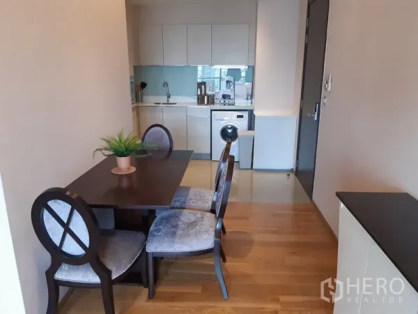 Condominium for rent in Watthana, Bangkok - Cozy dining nook for four leading to a modern kitchen and entry hallway with wood flooring.