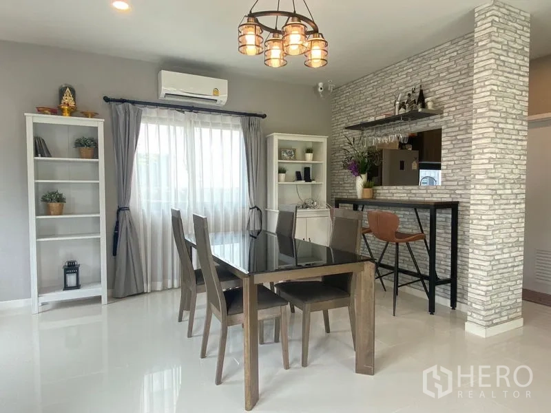 Detached House for rent in Bang Phli, Samut Prakan - Dining space with glass‑top table, brick feature wall, pendant lights and a breakfast bar.