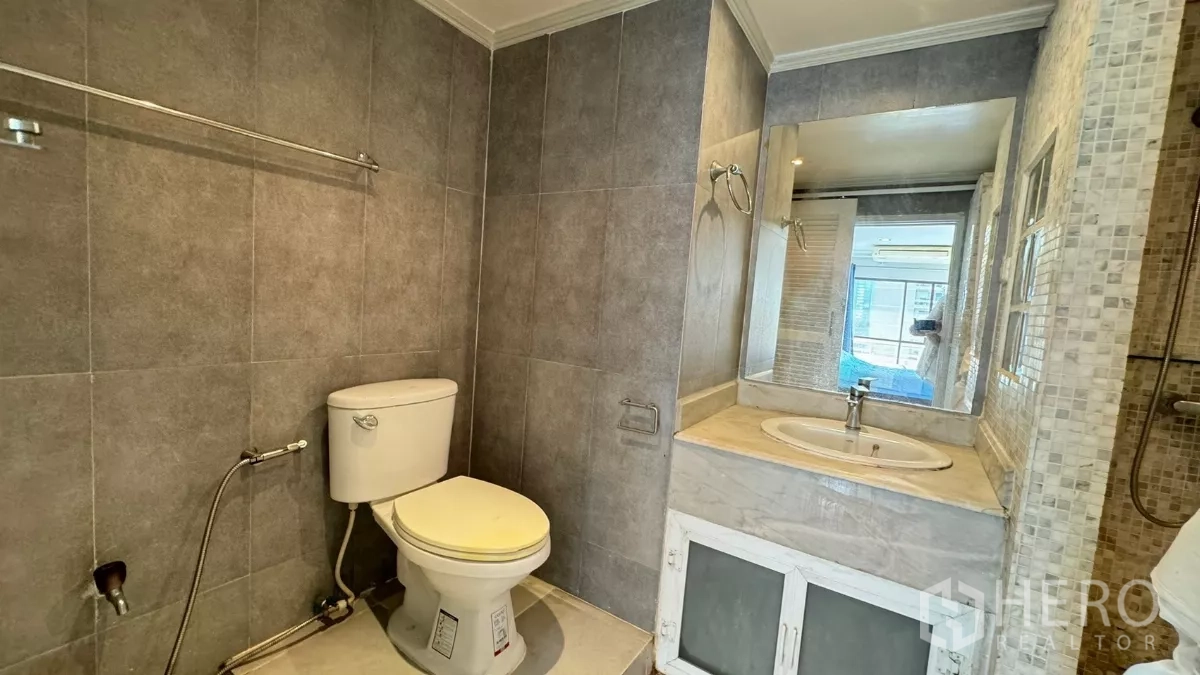 คอนโด ให้เช่าในKhlong Toei, Bangkok - ห้องน้ำผนังกระเบื้องสีเทา พร้อมเคาน์เตอร์อ่างล้างหน้าและโถสุขภัณฑ์