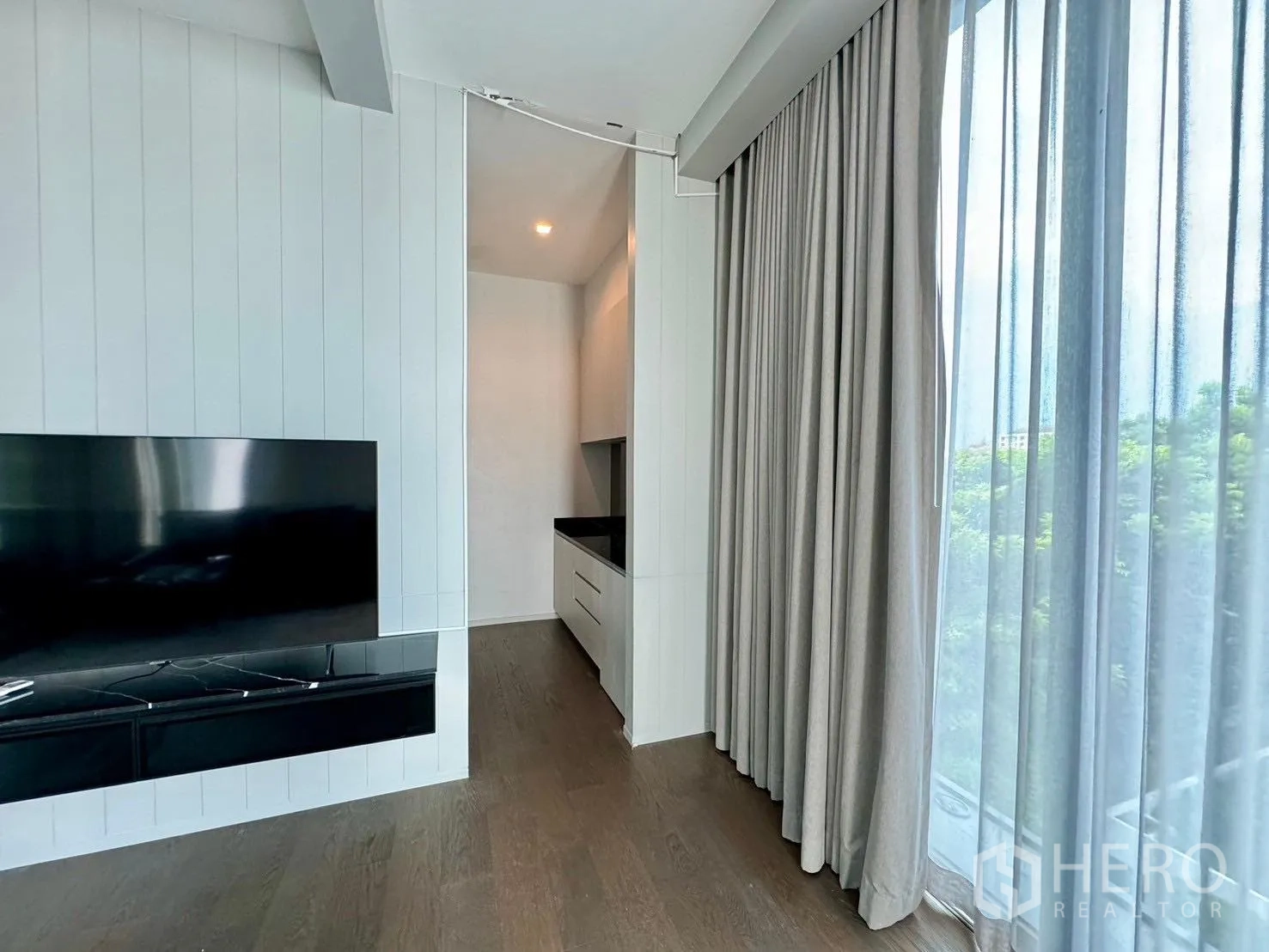 Detached House for rent or sale in Prawet, Bangkok - TV wall beside full-height curtains and bright window nook.