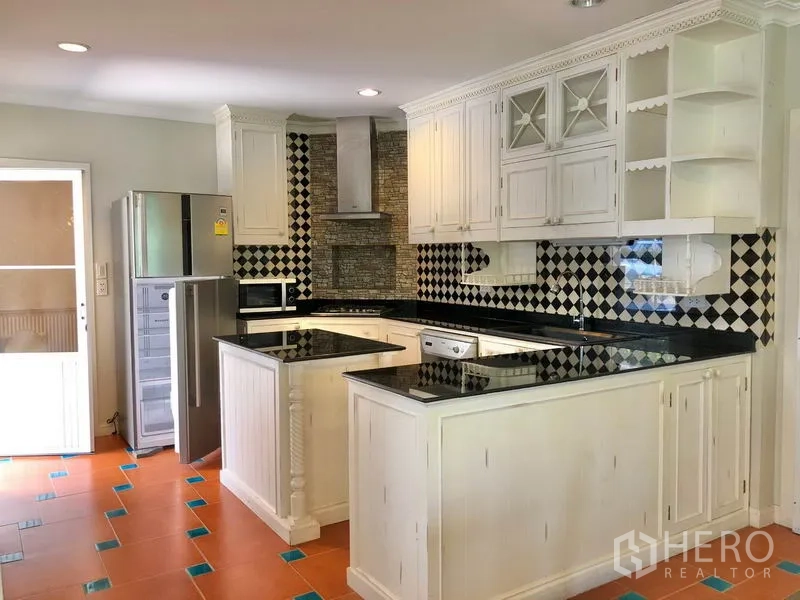 独立式住宅 出租在Mueang Samut Prakan, Samut Prakan - U 形厨房，黑色花岗岩台面、白色橱柜与黑白瓷砖背景，配不锈钢家电