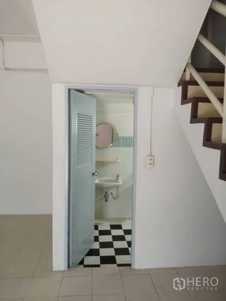 Warehouse for rent in Bang Phli, Samut Prakan - Compact restroom beneath the staircase with sink and black-and-white tiled floor.