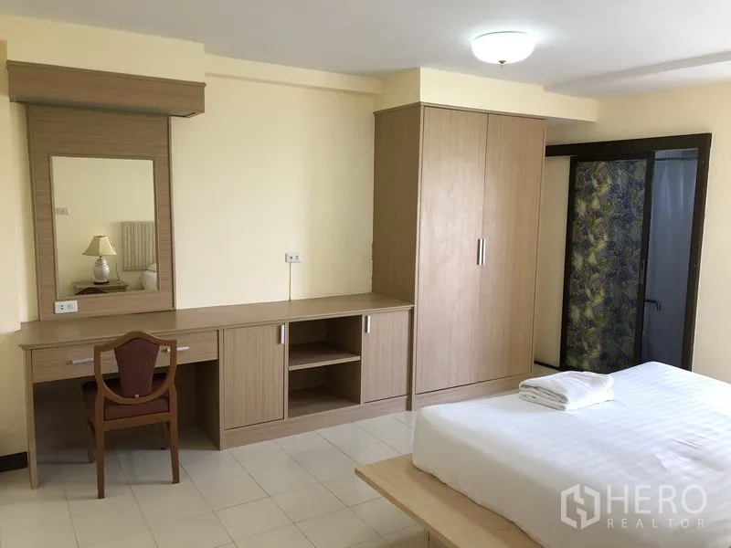 Apartment for rent in Suan Luang, Bangkok - Spacious bedroom with built‑in wardrobe, dressing table and a double bed.