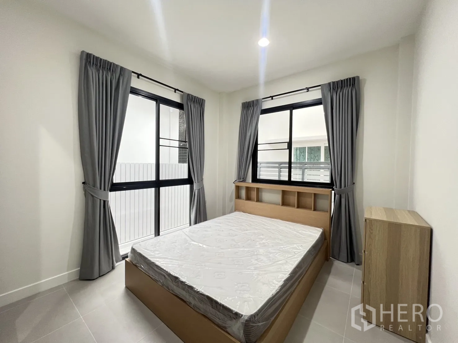 Detached House for rent in Saphan Sung, Bangkok - Bright bedroom with double bed, gray curtains, and large sliding windows.