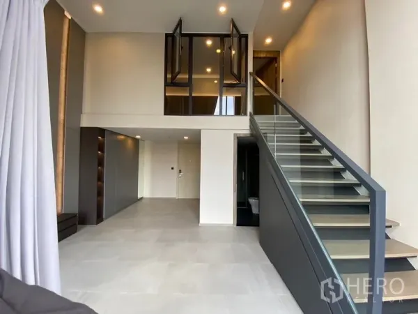 คอนโด ขายในPathum Wan, Bangkok - ห้องนั่งเล่นดับเบิลวอลุ่มสว่างไสว พร้อมหน้าต่างสูงและบันไดเรียบหรู