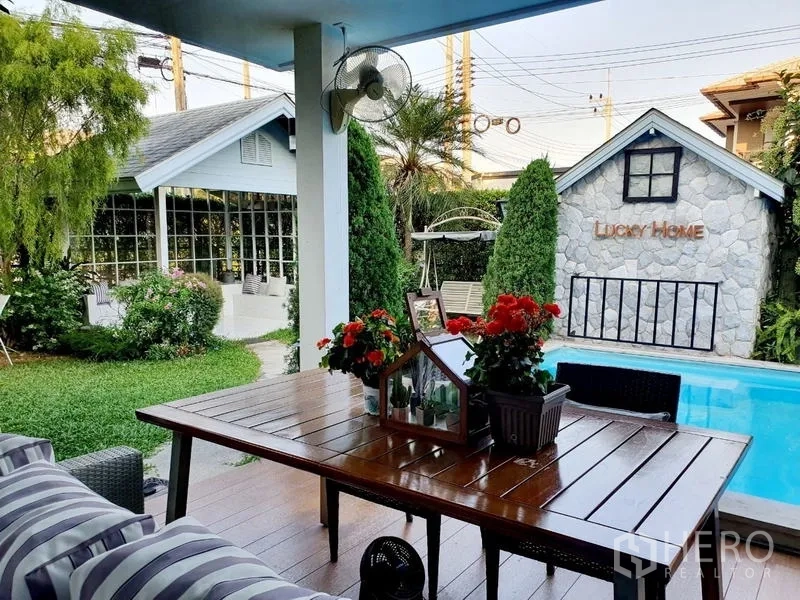 บ้าน ขายในLam Luk Ka, Pathum Thani - ระเบียงนั่งเล่นมีหลังคาพร้อมชุดโต๊ะไม้ มองเห็นสวนจัดและสระว่ายน้ำส่วนตัวกับศาลา.