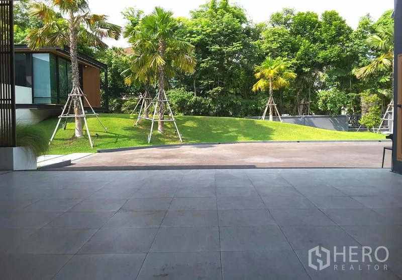 บ้าน ให้เช่าหรือขายในLam Luk Ka, Pathum Thani - เฉลียงกว้างมองออกไปยังลานหน้าบ้านและเนินหญ้าพร้อมต้นปาล์ม