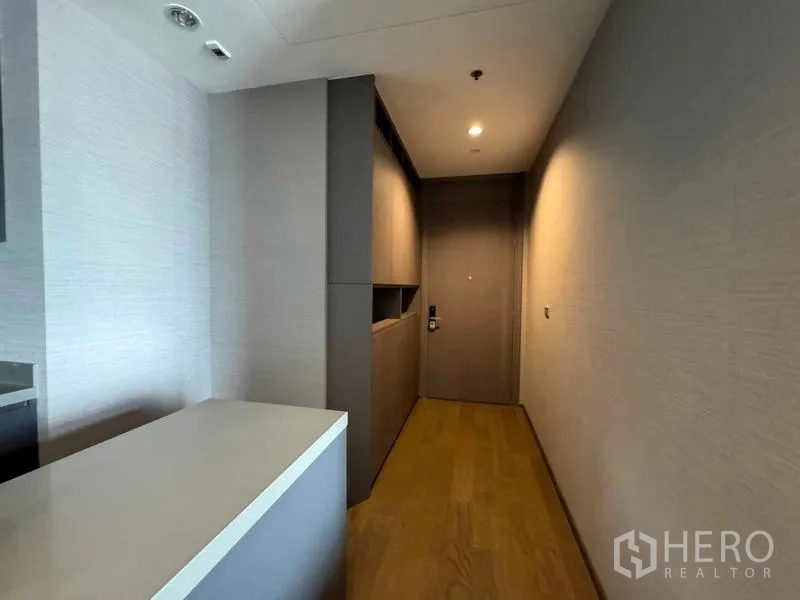 Condominium for sale in Bang Rak, Bangkok - Media wall with open shelving, flat‑screen TV and balcony access in the living room.