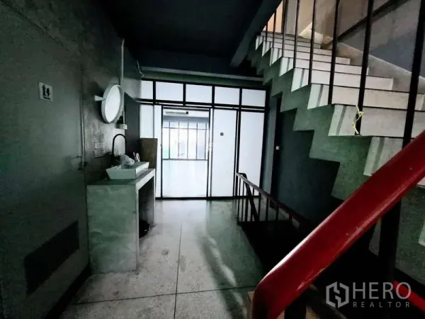 店屋 出租在Bang Rak, Bangkok - 楼梯平台带洗手台，前方为玻璃隔断的办公室空间。