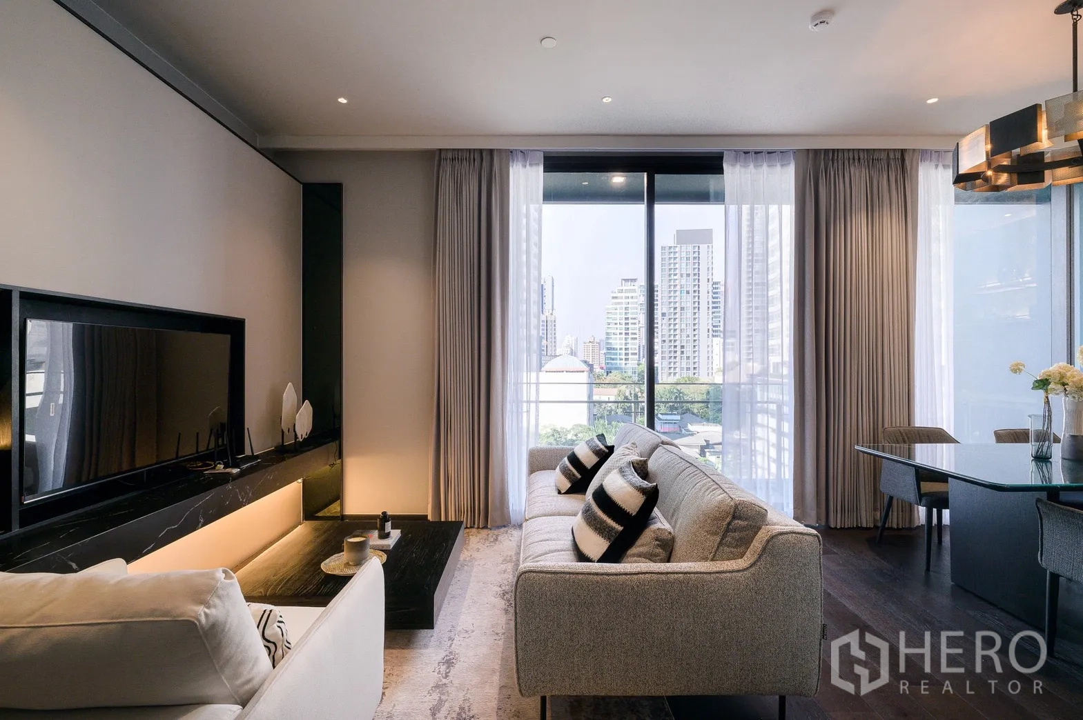 Condominium for rent or sale in Watthana, Bangkok - Bright living room with floor-to-ceiling windows, city skyline view and sliding doors to a balcony.