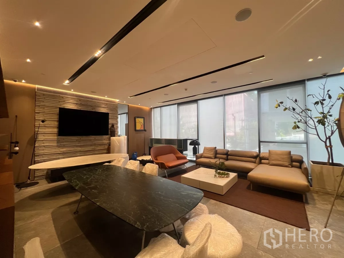 พื้นที่ขายปลีก ให้เช่า - มุมเลานจ์พร้อมโซฟาเซกชัน โต๊ะกลาง กระจกบานใหญ่ และไฟเพดานบรรยากาศ.